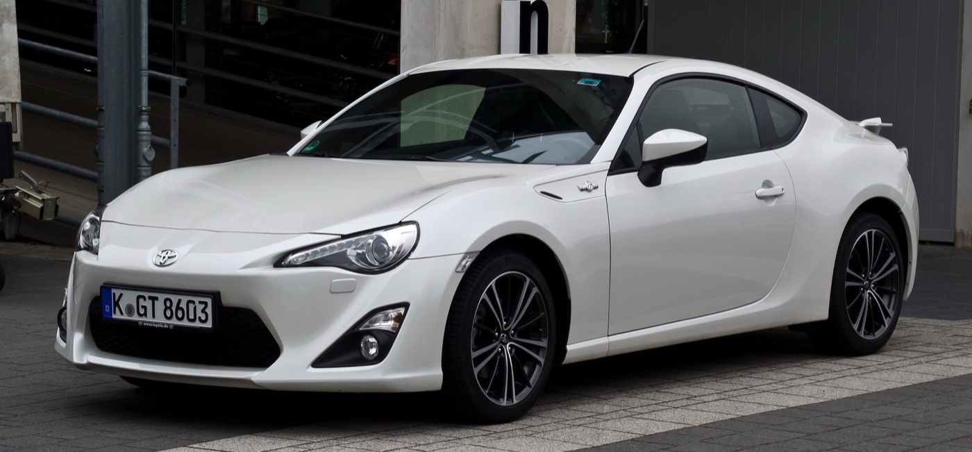 White Toyota GT86 coupé in front three-quarter view, parked on a paved street