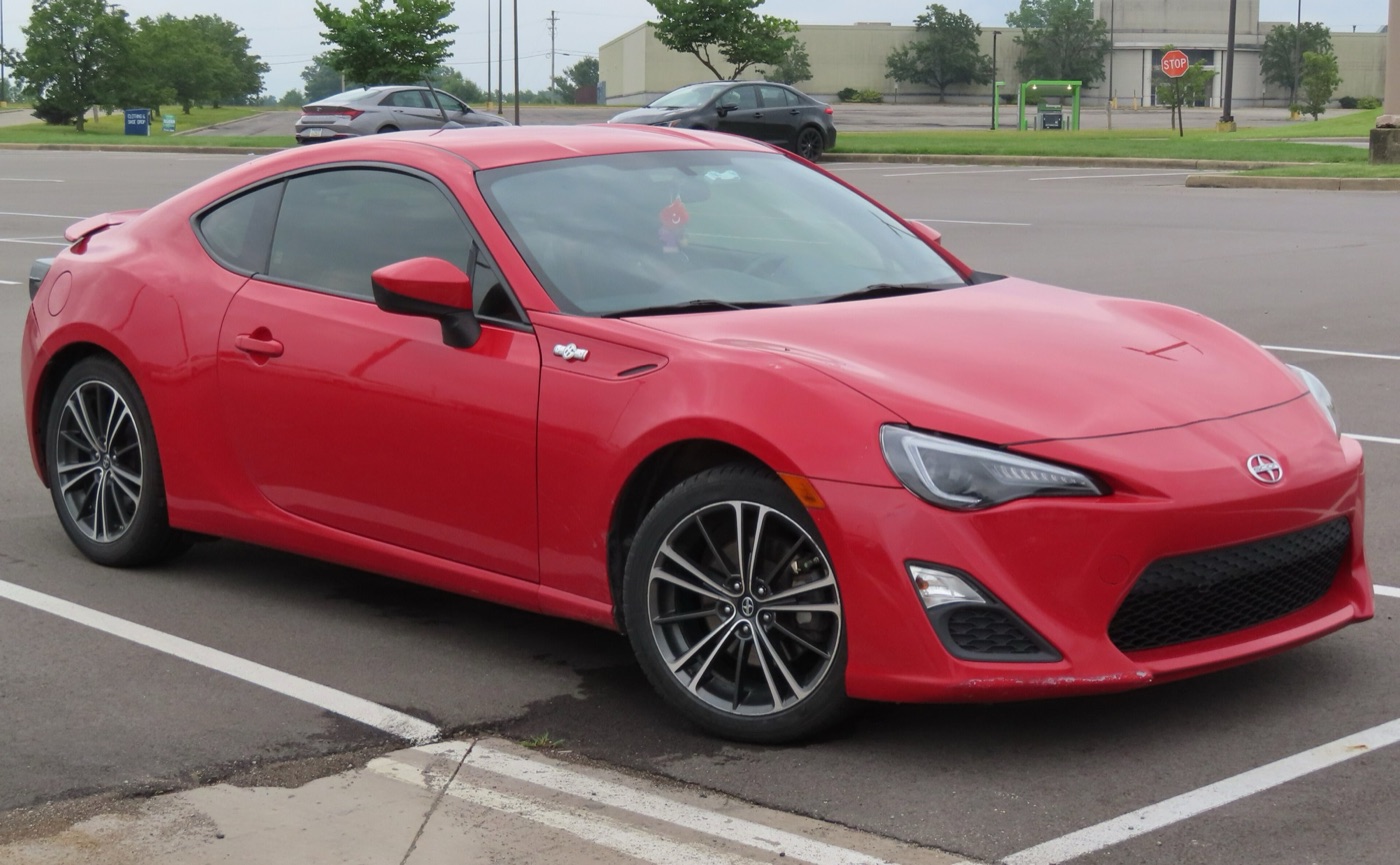 Red 2013 Scion FR-S coupe with the Scion badge on its nose, parked in a car park
