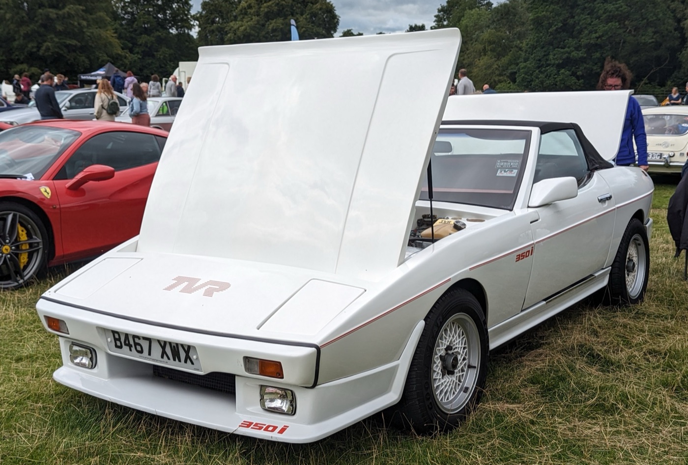 White TVR 350i wedge convertible with red 350i stripes and its bonnet raised at a car show