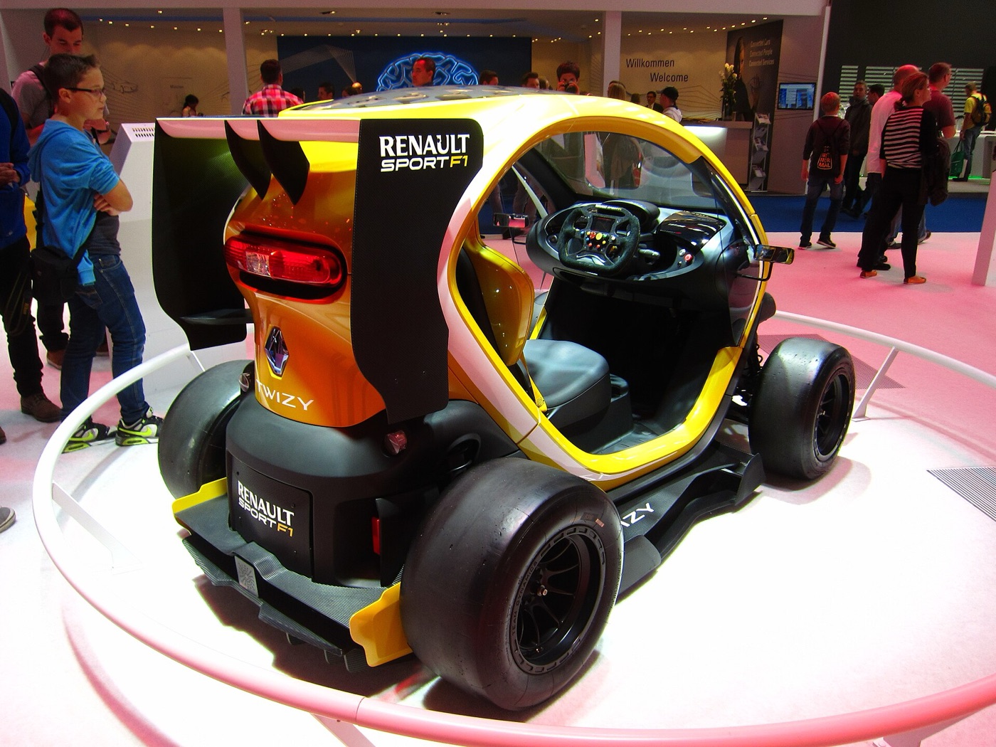 Yellow and black Twizy concept from the rear three-quarter, showing the rear wing, slick tyres and a race-style steering wheel through the open side