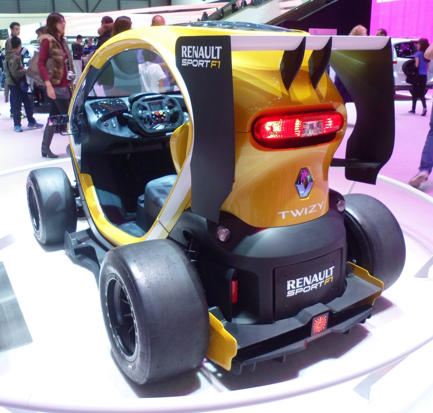 Rear view of the yellow Twizy concept with its wing, diffuser and the red rain light lit at the bottom centre
