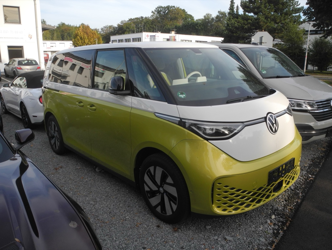 Yellow and white Volkswagen ID. Buzz electric van with a large VW badge on its two-tone nose, parked in Ratingen