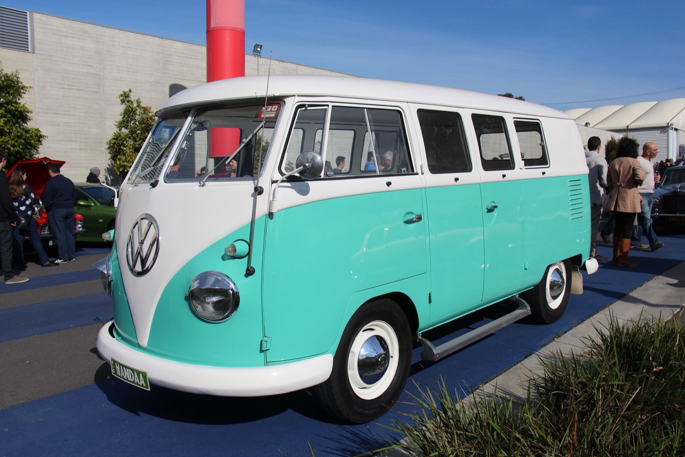Turquoise and white 1956 Volkswagen T1 Kombi with a split windscreen and V-shaped nose, parked at an outdoor car show