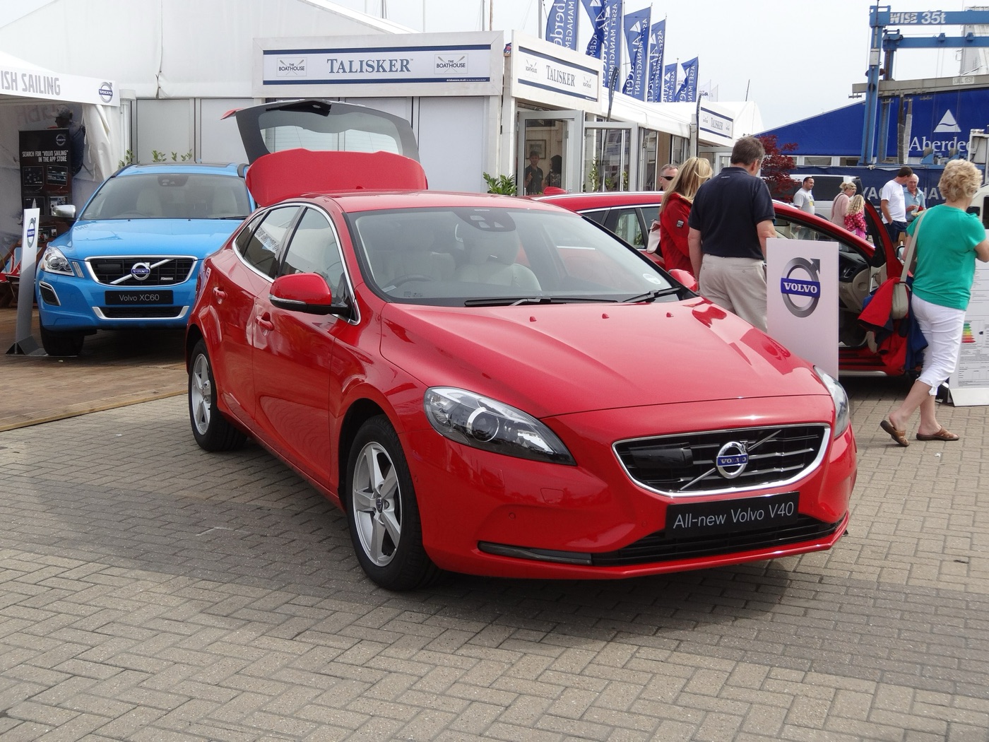 Red Volvo V40 with tailgate open and an All-new Volvo V40 plate, on the Volvo stand at Cowes Yacht Haven beside a blue XC60