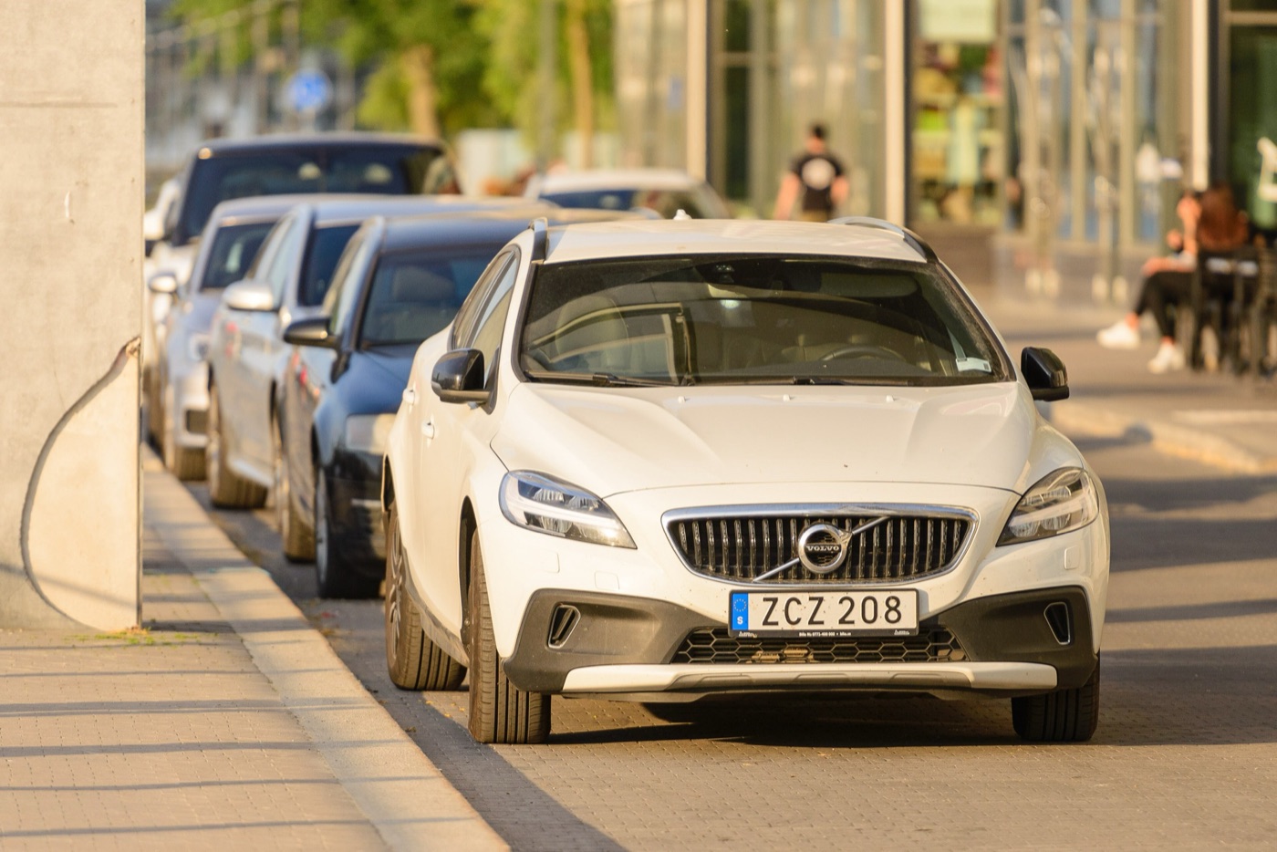 White facelifted Volvo V40 Cross Country with black bumper inserts, silver skid plate and Swedish number plate, parked at a kerb