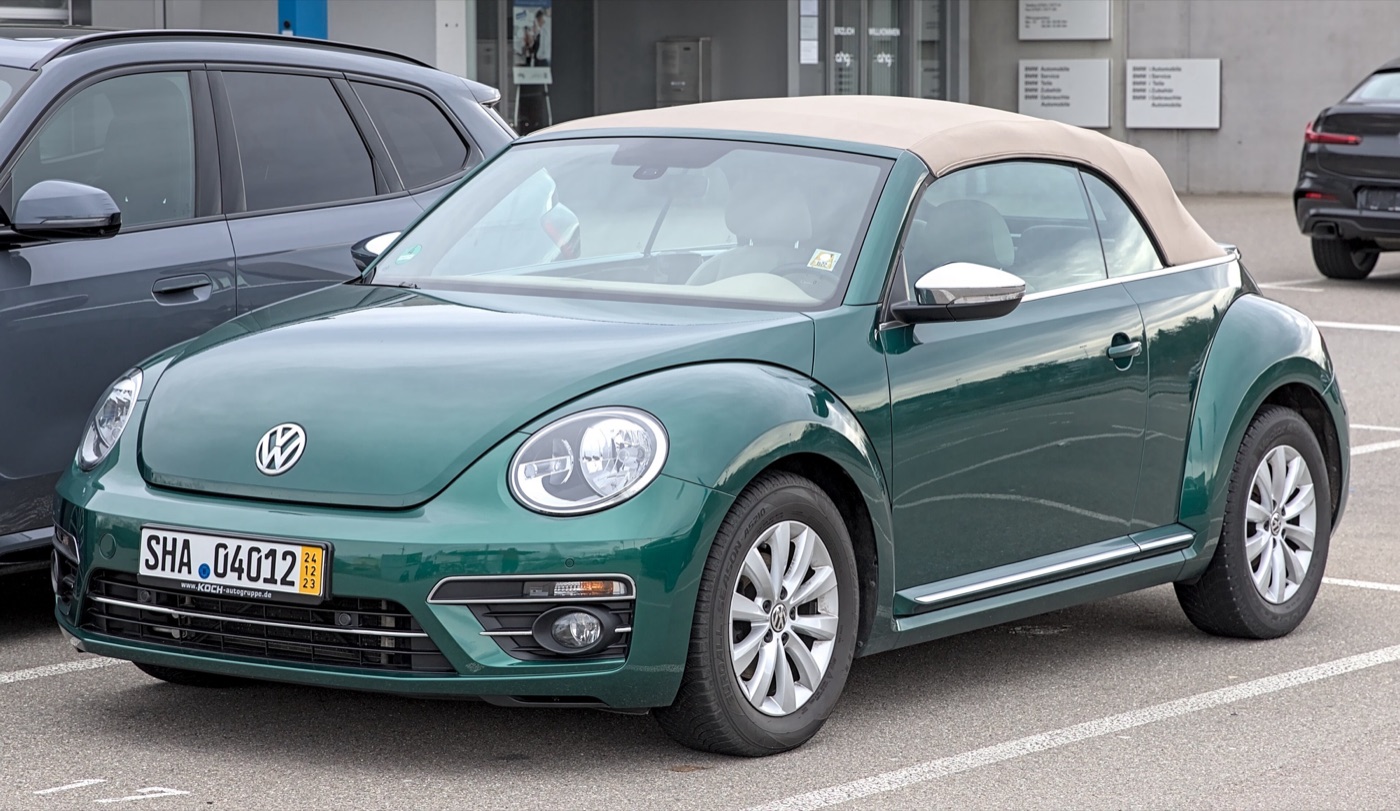 Green facelifted Volkswagen Beetle Cabriolet with a beige fabric roof raised, parked in Böblingen