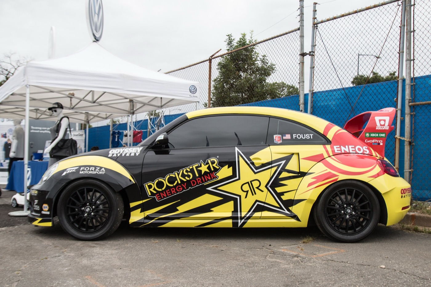 Yellow, black and red Volkswagen Beetle rallycross car with a large rear wing and Foust on the rear window