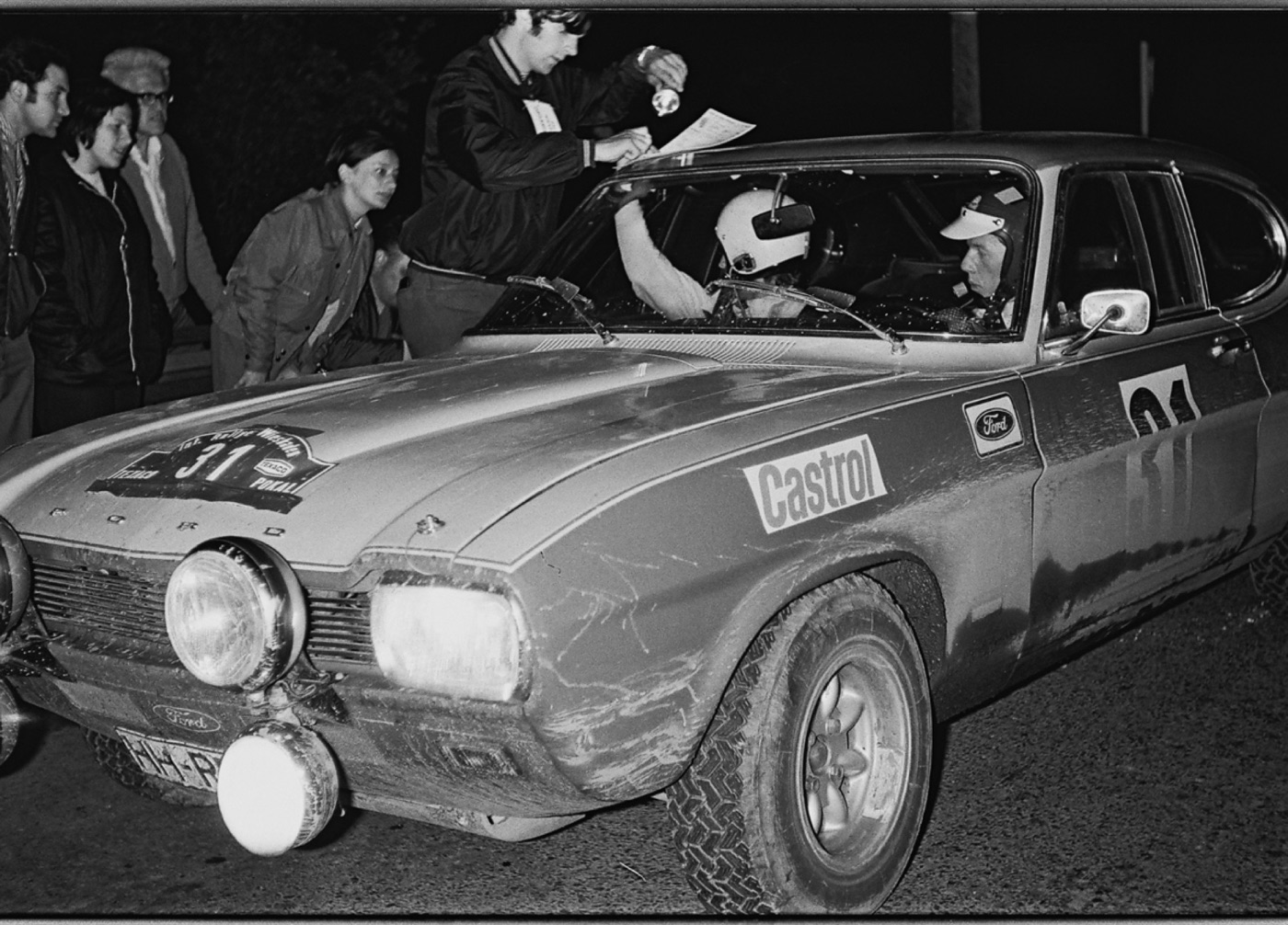 Walter Röhrl in a helmet at the wheel of a Ford Capri, number 31, at night with officials at the window