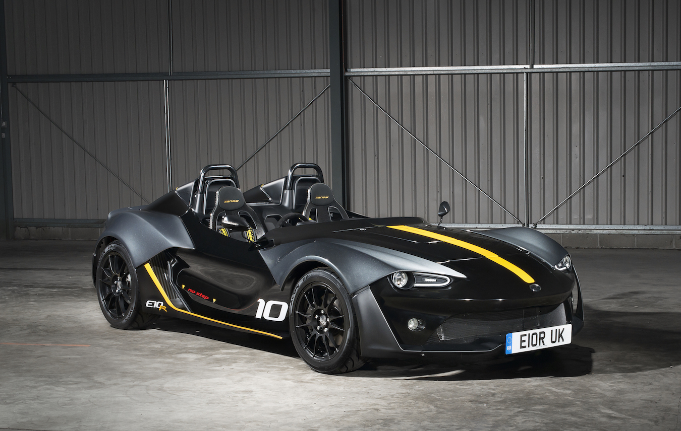 Black and grey Zenos E10 R with yellow stripes, number 10 on its side and the E10R badge, in a warehouse