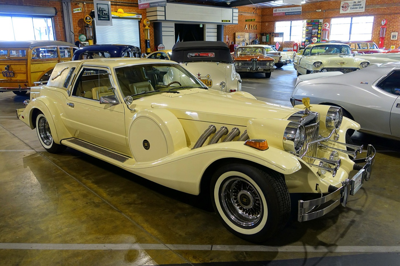 Cream Zimmer Golden Spirit coupé with long sweeping wings, flexible chrome side exhausts, a landau roof and whitewall tyres, in a car museum